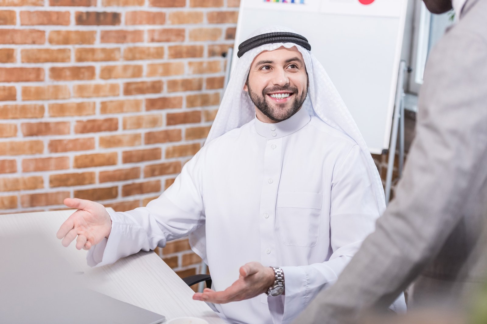 Arabian businessman smiling and gesturing in office